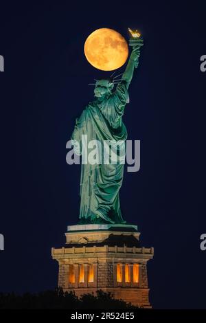 Statue of Liberty Moon - Naher Blick auf den oberen Teil von Lady Liberty im Hafen von New York, fast wie ein Supermond. Dieses Bild ist ein Stockfoto
