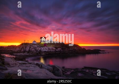 Nubble Lighthouse Sunrise - Blick auf einen wunderschönen dramatischen Himmel mit aufgehender Sonne hinter dem berühmten Nubble Light am Cape Neddick in York Stockfoto