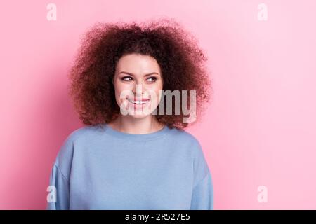 Portrait eines optimistischen, reizenden Mädchens trägt ein blaues Sweatshirt, das glücklich aussieht, leerer Raum, neuer Friseursalon isoliert auf pinkfarbenem Hintergrund Stockfoto