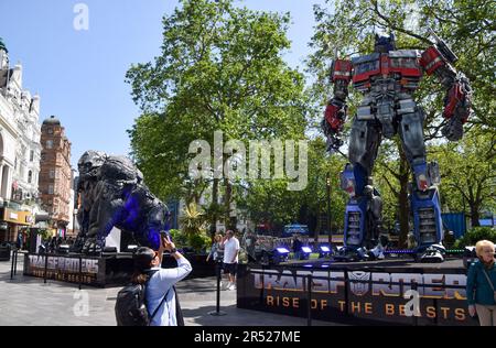 London, Großbritannien. 26. Mai 2023 Eine Frau fotografiert die Statue von Optimus Prime. Riesige Transformatoren wurden auf dem Leicester Square vor der Premiere des nächsten Films, Transformers: Rise of the Beasts, installiert. Stockfoto