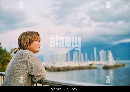 Außenporträt eines glücklichen Jugendlichen Jungen, der die wunderschöne Wasserlandschaft bewundert, Bild aufgenommen in Lausanne, Schweiz Stockfoto