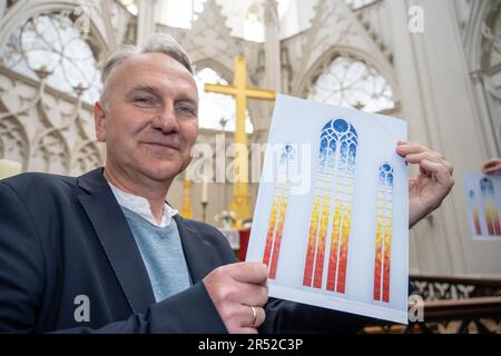 31. Mai 2023, Mecklenburg-Vorpommern, Greifswald: Tilman Beyrich, Pastor in St. Nikolai Kathedrale, zeigt ein Design des dänisch-isländischen Künstlers 'lafur Elíasson. Neben einem umfangreichen Kulturprogramm wird der 250. Geburtstag des Malers Caspar David Friedrich im kommenden Jahr auch bleibende Spuren in seiner Heimatstadt Greifswald hinterlassen. Die neuen Ostfenster in der Kathedrale sollen im April eröffnet werden. Der international bekannte zeitgenössische Künstler Elíasson entwirft ein modernes Kirchenfenster für St. Nikolai Kathedrale - das Taufwerk der berühmten Romantik. Stockfoto