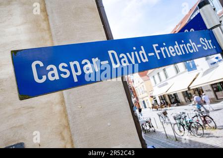 31. Mai 2023, Mecklenburg-Vorpommern, Greifswald: Straßenschild mit der Aufschrift „Caspar-David-Friedrich-Str.“ Neben einem umfangreichen Kulturprogramm soll der 250. Geburtstag des Malers Caspar David Friedrich im kommenden Jahr auch bleibende Spuren in seiner Heimatstadt Greifswald hinterlassen. Die neuen Ostfenster in der Kathedrale sollen im April eröffnet werden. Nach Angaben der Stadt soll das Jubiläumsjahr in der Kathedrale feierlich am 20. Januar 2024 eröffnet werden. Es wurden bereits 160 Ereignisse registriert. Konzerte mit Modern und classica Stockfoto