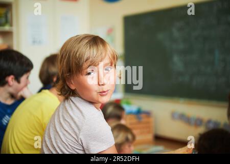 Süßer kleiner Junge, der im Klassenzimmer arbeitet, Bildung, wieder-zur-Schule-Konzept Stockfoto