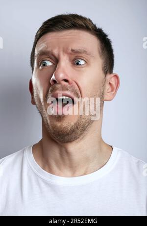 Emotional verängstigter Mann sieht mit verängstigtem Ausdruck, sieht etwas Schreckliches, sieht nervös aus, zeigt Phobie. Menschliche Reaktionen und Emotionen Stockfoto