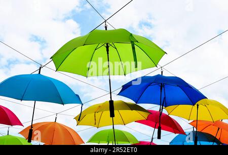 Farbenfroher Sonnenschirm. Helle Regenschirme, die über Kopf auf Metalldrähten hängen. Klimawandel, Umwelt und Konzept der globalen Erwärmung. Sommer Stockfoto