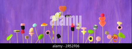verschiedene Süßigkeiten und Süßigkeiten, Nahaufnahme, Panoramaformat, violetter Hintergrund Stockfoto