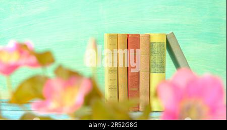 Lesen und Entspannen im Frühling und Sommer, Bücherreihe und verschwommene Clematis Blumen im Vordergrund, selektiver Fokus, kostenloser Kopierbereich Stockfoto
