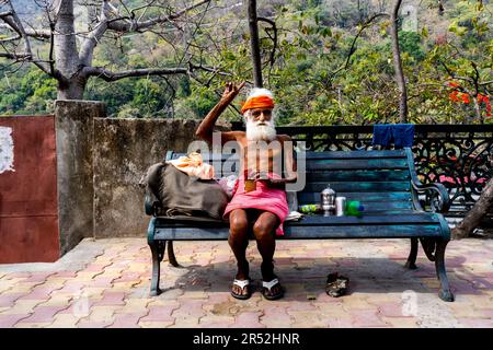 Rishikesh, Uttarakhand, Indien - 28.03.2023: Lustiges Porträt eines bärtigen Pilgers in orangefarbener Kleidung. Hochwertiges Foto Stockfoto