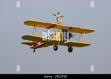 Ein Boeing A-75L300 Stearman Doppeldecker der Wing Walk Company in Aktion mit Wing Walkern am Headcorn Aerodrome Kent England Stockfoto