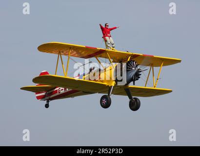 Ein Boeing A-75L300 Stearman Doppeldecker der Wing Walk Company in Aktion mit Wing Walkern am Headcorn Aerodrome Kent England Stockfoto