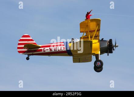 Ein Boeing A-75L300 Stearman Doppeldecker der Wing Walk Company in Aktion mit Wing Walkern am Headcorn Aerodrome Kent England Stockfoto