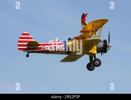 Ein Boeing A-75L300 Stearman Doppeldecker der Wing Walk Company in Aktion mit Wing Walkern am Headcorn Aerodrome Kent England Stockfoto