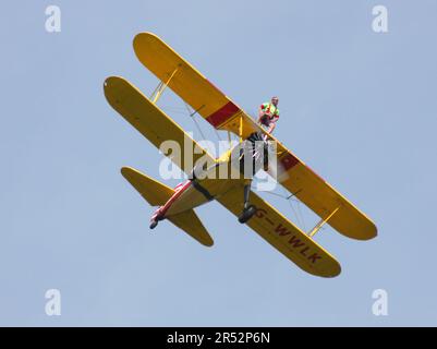 Ein Boeing A-75L300 Stearman Doppeldecker der Wing Walk Company in Aktion mit Wing Walkern am Headcorn Aerodrome Kent England Stockfoto