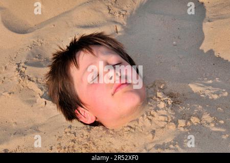 Das Kind liegt im Sand, Berlin, Deutschland Stockfoto