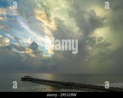 Aus der Vogelperspektive die Brücke erstreckt sich bei schönem Sonnenuntergang bis ins Meer. Atemberaubende Wolken, die sich am blauen Himmel bewegen. Wunderschöne Sonnenuntergangslandschaft, herrliches Licht der Natur Stockfoto