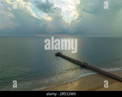 Aus der Vogelperspektive die Brücke erstreckt sich bei schönem Sonnenuntergang bis ins Meer. Atemberaubende Wolken, die sich am blauen Himmel bewegen. Wunderschöne Sonnenuntergangslandschaft, herrliches Licht der Natur Stockfoto