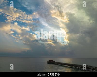 Aus der Vogelperspektive die Brücke erstreckt sich bei schönem Sonnenuntergang bis ins Meer. Atemberaubende Wolken, die sich am blauen Himmel bewegen. Wunderschöne Sonnenuntergangslandschaft, herrliches Licht der Natur Stockfoto