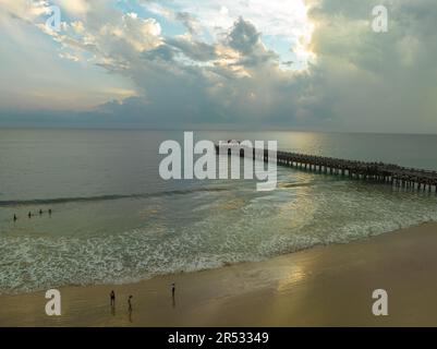 Aus der Vogelperspektive die Brücke erstreckt sich bei schönem Sonnenuntergang bis ins Meer. Atemberaubende Wolken, die sich am blauen Himmel bewegen. Wunderschöne Sonnenuntergangslandschaft, herrliches Licht der Natur Stockfoto