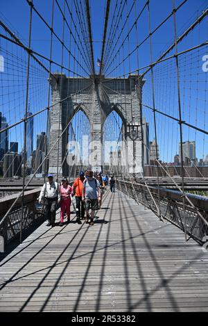 Besucher auf dem Fußgängerweg der Brooklyn Bridge mit der Skyline von Manhattan im Hintergrund. Stockfoto