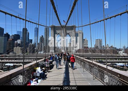 Besucher auf dem Fußgängerweg der Brooklyn Bridge mit der Skyline von Manhattan im Hintergrund. Stockfoto