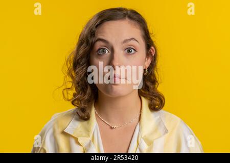 Überraschend witzig, witzig, verspielte junge Frau, die Fische grimmig schmollt, erstickt, mit schockiertem, idiotischen Ausdruck schaut, Entengesicht macht, rummacht. Mädchen mit gelbem Hintergrund Stockfoto