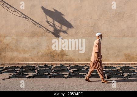 Ein Mann geht vorbei an Häuten, die vor der Ben Youssef Moschee, Marrakesch, Marokko trocknen Stockfoto