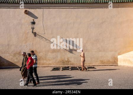 Männer gehen vorbei an Fellen, die vor der Ben Youssef Moschee, Marrakesch, Marokko trocknen Stockfoto