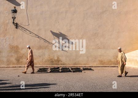 Männer gehen vorbei an Fellen, die vor der Ben Youssef Moschee, Marrakesch, Marokko trocknen Stockfoto