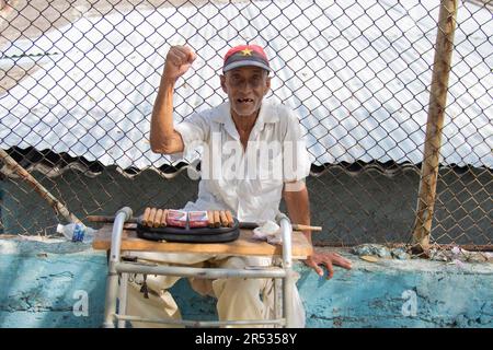 Ein älterer Mann lächelt, während er Zigaretten und Zigarren in einem kleinen Laden in Havanna, Kuba, verkauft. Stockfoto