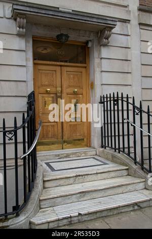 Doppelte Holztür mit Messingbeschlägen flankiert von Metallgeländern, die zum Eingang einer privaten medizinischen Praxis in der Harley Street, London England, Großbritannien führen Stockfoto