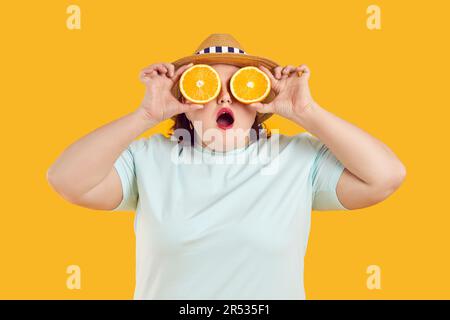 Porträt einer lustigen fetten Frau, die ihre Augen mit orangefarbenen Scheiben wie eine Brille bedeckt Stockfoto