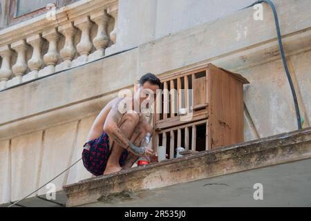 Ein Kubaner füttert seine Vögel auf dem Dach seines Gebäudes in einem Vogelkäfig in Havanna, Kuba Stockfoto