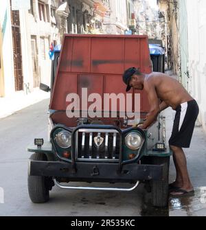 Ein Kubaner, der an seinem alten Auto auf der Straße in Havanna, Kuba, arbeitet. Stockfoto