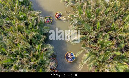 Aus der Vogelperspektive bei einer Bootstour mit einem Kokoskorb im Palmenwald im Dorf Cam Thanh, Hoi an, Vietnam. Touristen machen einen Ausflug auf dem Fluss Thu Bon Stockfoto