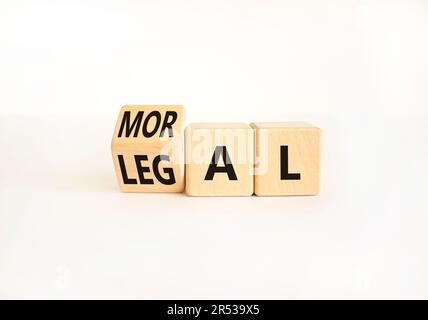 Rechtliches oder moralisches Symbol. Ein Geschäftsmann verwandelt Holzwürfel und ändert das Wort "Legal" in "Moral" auf einem schönen weißen Tischhintergrund. Business und Le Stockfoto