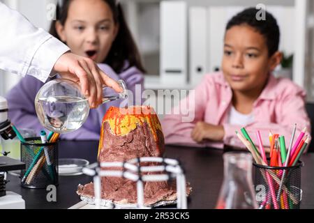 Kleine Kinder experimentieren mit Lehrer und chemischem Vulkan im Wissenschaftsunterricht Stockfoto