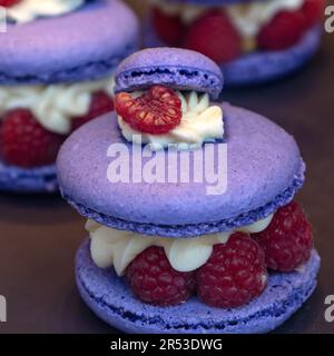 LONDON, UK - 27. MAI 2023: Schließung von Lavendelmakronen mit Buttercreme und Himbeeren in einer Patisserie im West End Stockfoto