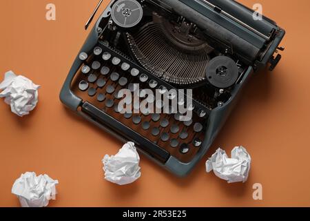 Vintage-Schreibmaschine mit zerknittertem Papier auf orangefarbenem Hintergrund Stockfoto