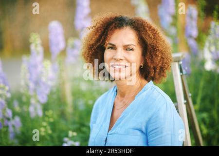 Außenporträt einer wunderschönen 50-jährigen Frau, die einen schönen Tag im Blumenpark oder Garten genießt, einen glücklichen und gesunden Lebensstil Stockfoto