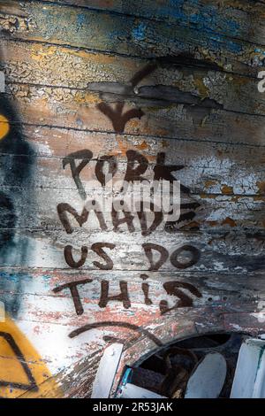 Schweinefleisch macht das. Graffiti auf einem alten, verlassenen und verlassenen Holzboot in Kaisaniemenranta in Helsinki, Finnland. Stockfoto