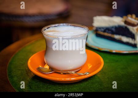 Kaffee mit Milchkaffee in einem durchsichtigen Glas und ein Stück Schokoladenkuchen Stockfoto