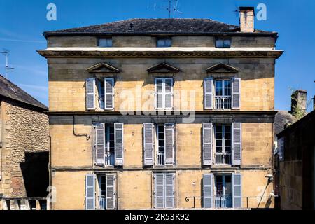 SARLAT-LA-CANEDA, FRANKREICH - 24. JULI 2018: Steinhaus mit blauen Fensterläden an einem Sommertag, Dordogne, Südwestfrankreich Stockfoto