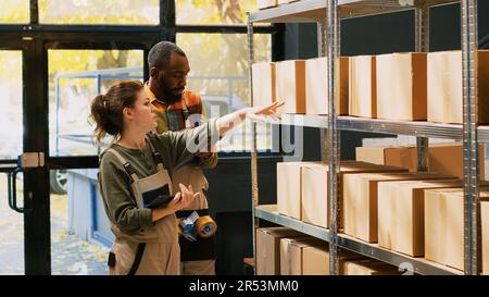 Team von Personen, die Fracht auf Regalen inspizieren und im Lager mit Lagerprodukten zusammenarbeiten. Verschiedene Kollegen prüfen die Bestandsliste von Waren auf Papier und Tablet-PC. Handgeführte Aufnahme. Stockfoto