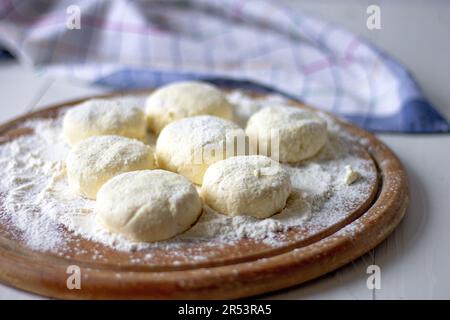 Rohe Hüttenkäse-Pfannkuchen. - Ungebackene Brötchen. Ukrainisches Gericht mit Hüttenkäse. Stockfoto