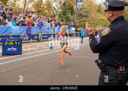 Ein NYPD-Offizier jubelt US-Marathonläufer Shalane Flanagan an an, während sie den New York City Marathon 2017 im Central Park, Manhattan, New York City gewinnt Stockfoto
