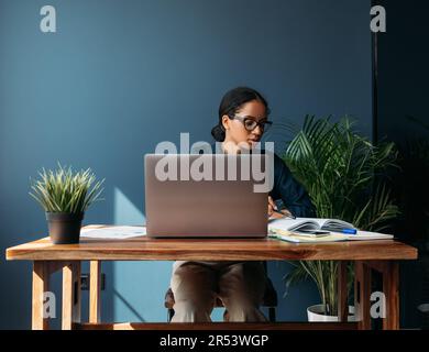 Junge Unternehmerin, die zu Hause am Tisch arbeitet Stockfoto
