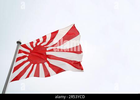 Japanische aufsteigende Sonnenfahne im Wind des Himmels Stockfoto