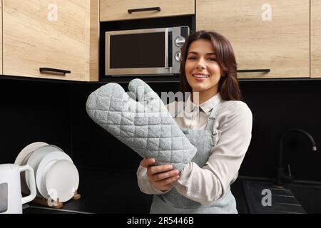 Frau mit Schürze und Ofenhandschuh in der Küche Stockfoto