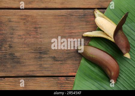 Köstliche lila Bananen und frisches Blatt auf Holztisch, Nahaufnahme. Platz für Text Stockfoto